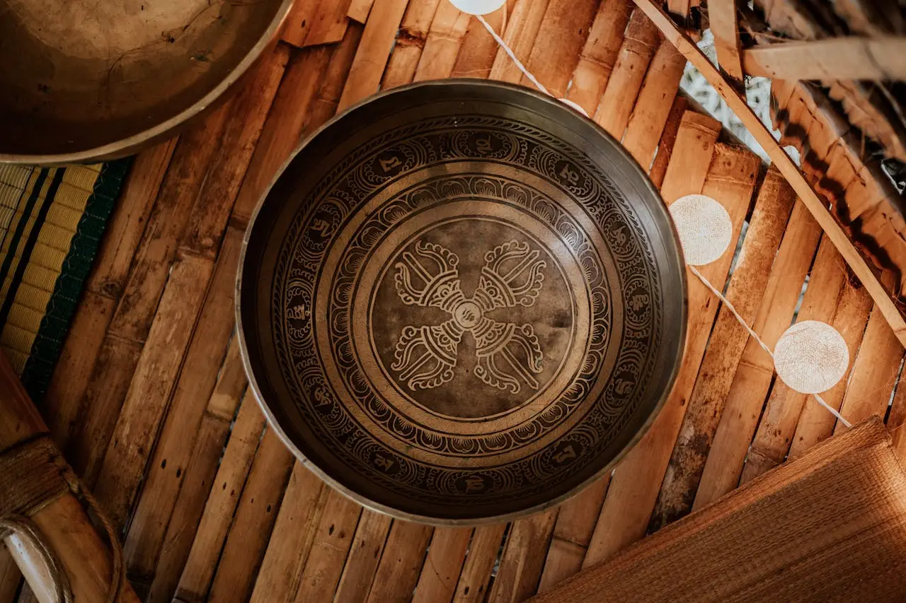 A traditional singing bowl resting on a bamboo surface with warm ambient lighting.