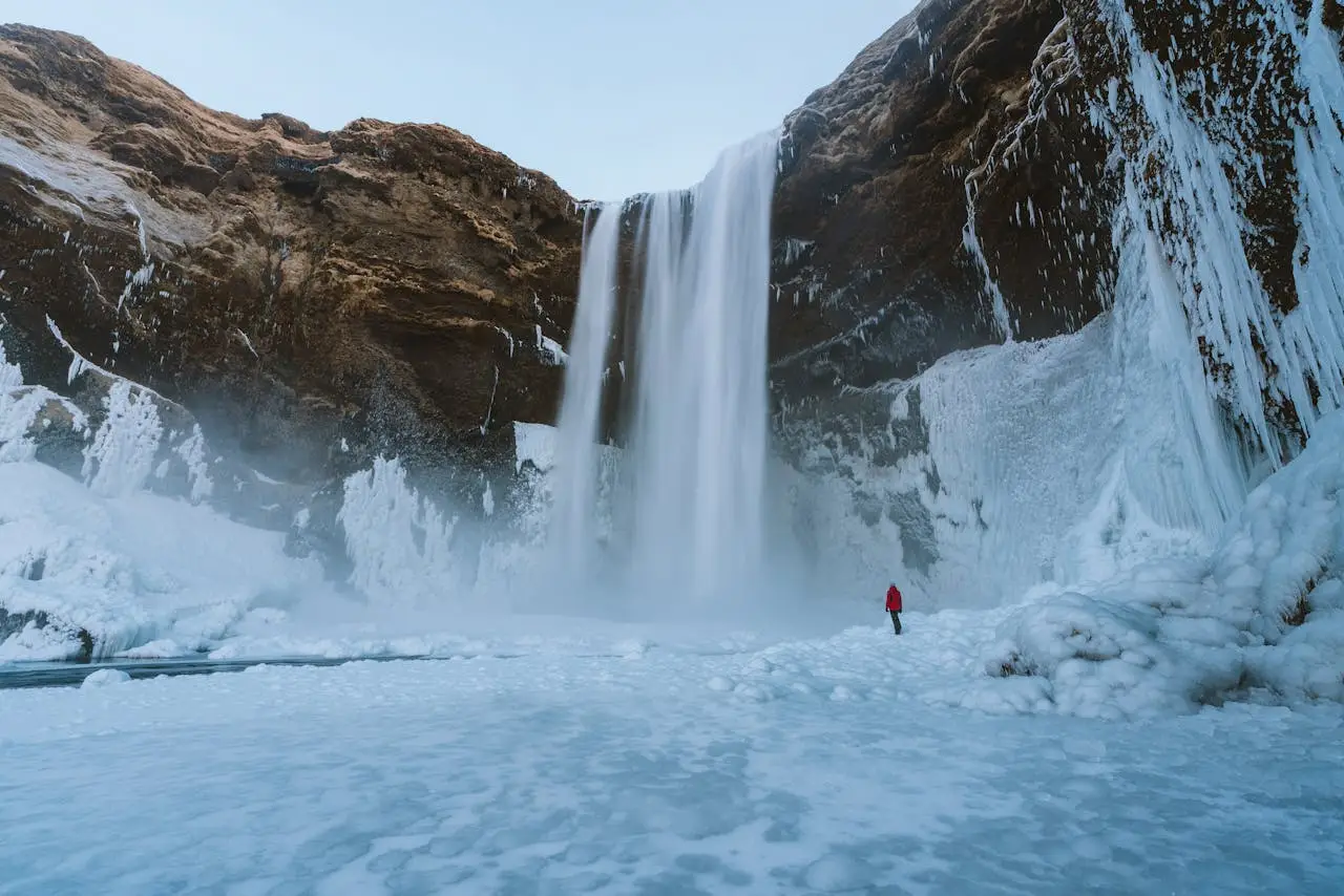 A breathtaking view of a towering waterfall amidst icy landscapes in Iceland.